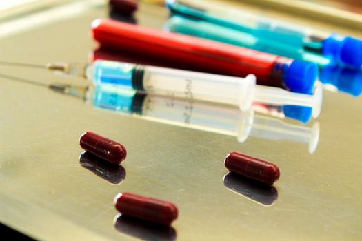 Syringe next to capsules and test tubes with blood and vaccine for Covid-19 virus