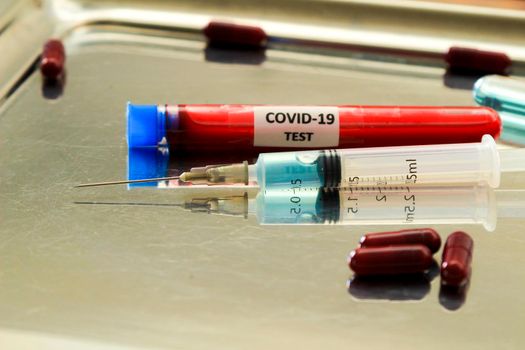 Syringe next to capsules and test tube with blood for Covid-19 virus test