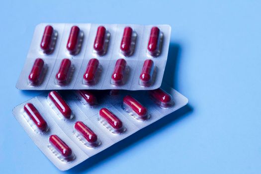 Red capsules blister packs on blue background