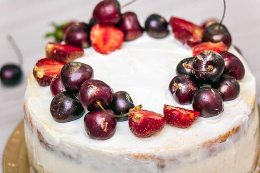 Cherries and strawberries with edible gold on top of cheesecake with coconut.