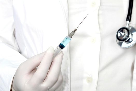 Medical professional on white uniform and surgery gloves holding a syringe with Covid-19 virus vaccine
