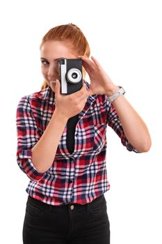 A portrait of a beautiful smiling young girl taking a photo with an old film camera, isolated on white background. Hobby concept.