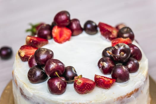 Cherries and strawberries with edible gold on top of cheesecake with coconut.