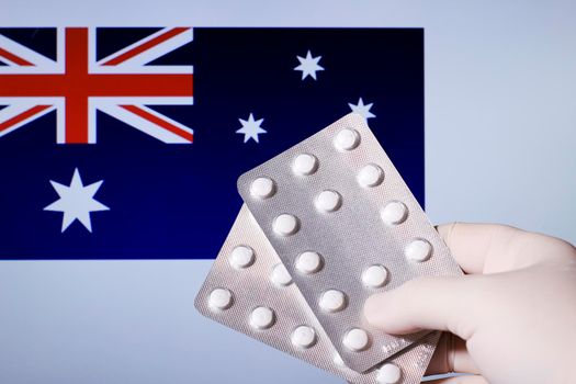 Hand in surgical glove holding pill blisters. German flag in the background