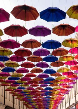 A row of colorful umbrellas decorating a street on  a sunny summer day