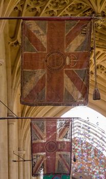Detail of two old flags hanging in the interior of Bath Abbey on a sunny day