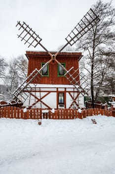 Decorated wooden mill with textured wall covered with a heavy snow in the village in Belarus.