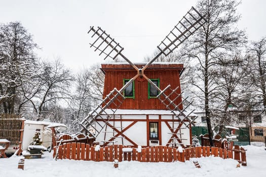 Decorated wooden mill with textured wall covered with a heavy snow in the village in Belarus.