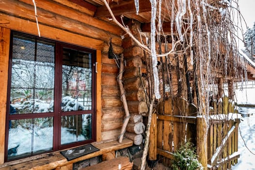 Decorated wooden house with textured wall covered with a heavy snow in the village in Belarus.