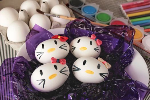 Alicante, Spain- March 18, 2021:Kitty easter eggs, paint and brush on purple cellophane paper