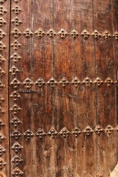 Old colorful carved wooden door with forged details in a small village in Castilla La Mancha community, Spain