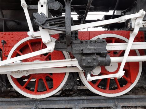 Wheels of an old steam locomotive on rails close-up.