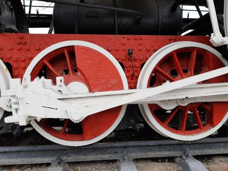 Wheels of an old steam locomotive on rails close-up.