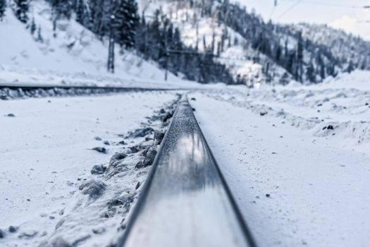 Railroad rails close up on the background of snowy mountains in winter