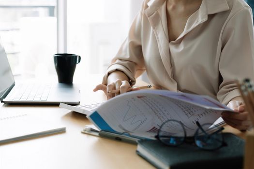 Close up Business woman or accountant using calculator with computer laptop, Business accounting, budget and loan paper at home.