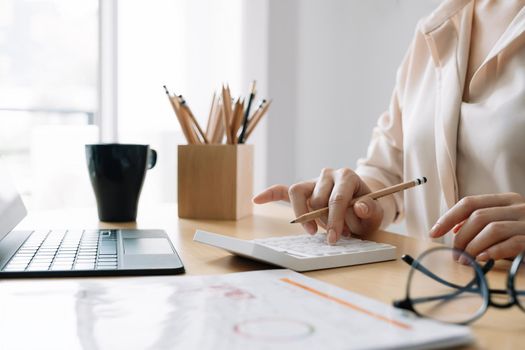 Close up Business woman or accountant using calculator with computer laptop, Business accounting, budget and loan paper at home.