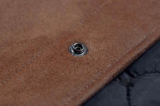 Close-up of a button-down button on a faux suede jacket.