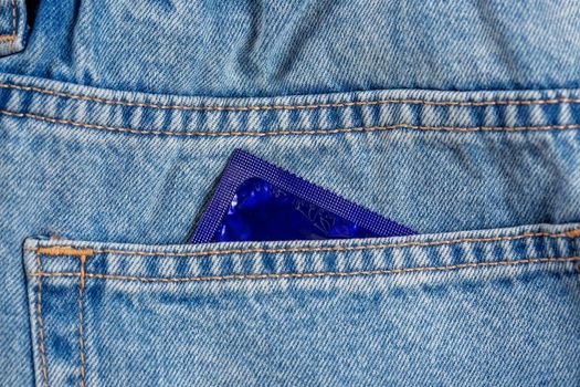 Close-up of a pocket of blue jeans from which a condom sticks out, safe sex concept