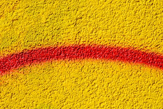 Detail of a yellow painted rough wall with red curved line