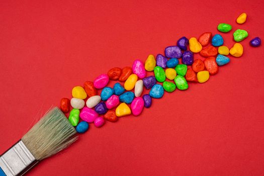 a brush leaves a trail of colored pebbles