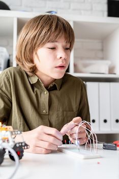 12 year old boy constructing a robot car sitting at the table