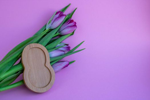 Tulips on a pink background and 8 made of wood.Concept March 8.