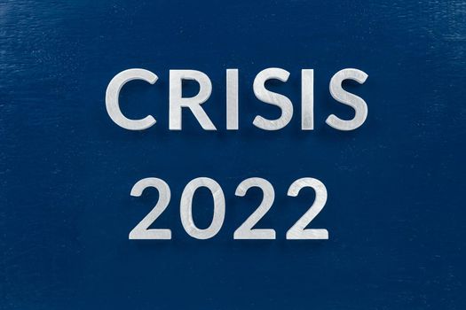 the words crisis 2022 laid with luminium letters on blue painted board background