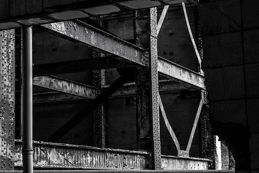 Close-up of the beams of an old rusty metal frame through a hole in a wall inside a derelict building