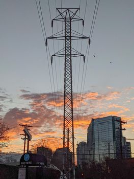 high voltage power lines and city skyline at sunrise