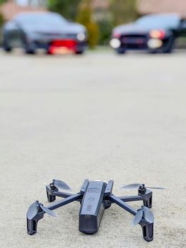 selective view of drone with bokeh of two sports cars beyond