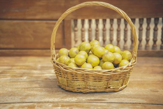 fresh orange tangerine fruit in rattan wicker basket on wooden chair