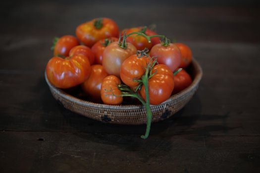 fresh raw red tomatoes in basket on wooden table