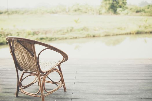 wicker rattan chair on balcony terrace patio for resting near pond