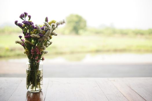 flower bouquet in glass vase on wooden table at patio