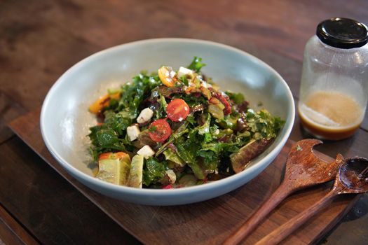 mixed vegetable salad with olive oil on wooden table