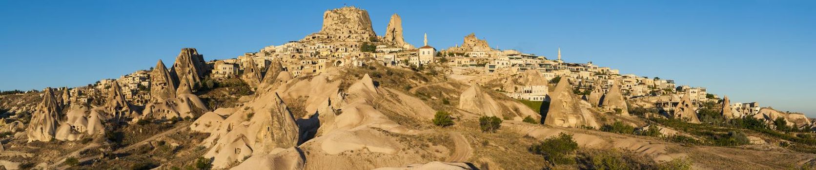 Ancient town and a castle of Uchisar dug from a mountains after sunrise, Cappadocia, Turkey.Panorama