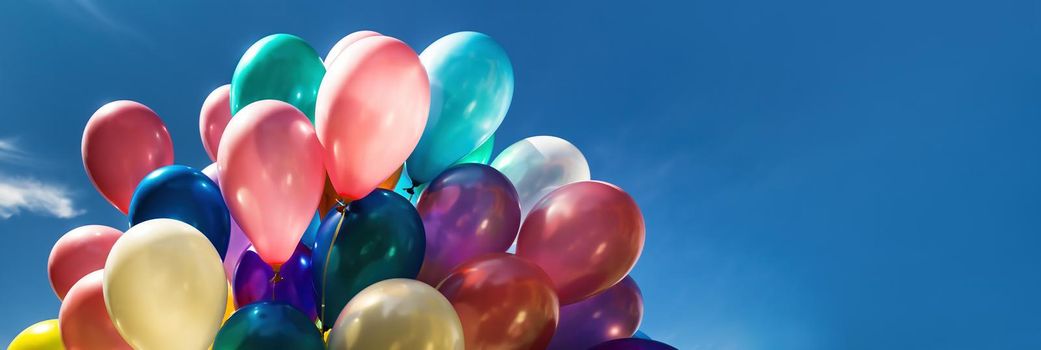 Lots of colorful balloons on the blue sky background with clouds