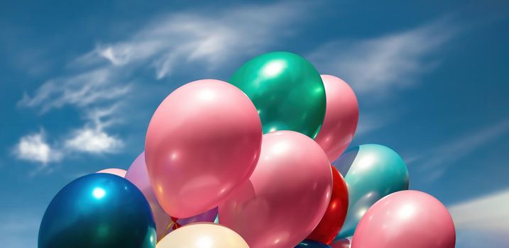 Lots of colorful balloons on the blue sky background with clouds