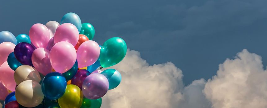 Bunch of colorful balloons against cloudy sky