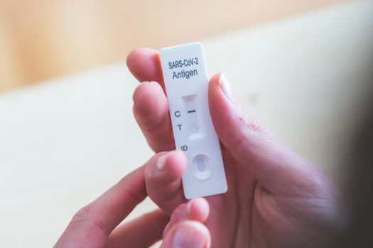 Close up of fingers holding express antigen covid test, negative result