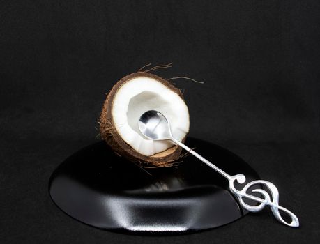 Half a coconut with pulp and a dessert spoon on a gray background.Half a coconut close up.