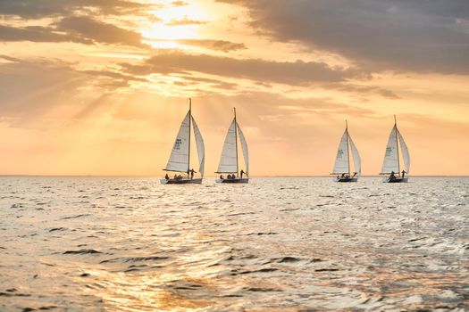 Russia, St.Petersburg, 05 September 2020: Some sailboats in a list goes by sea, the sky of pink color, the storm sky, regatta. High quality photo