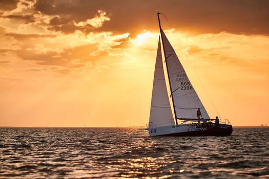 Russia, St.Petersburg, 05 September 2020: The lonely sailboat in a list goes by sea, the sky of pink color, the storm sky. High quality photo