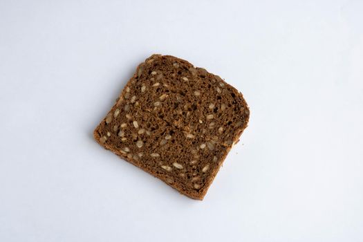 Slice of whole-grain dark bread, isolated on a white background close-up.