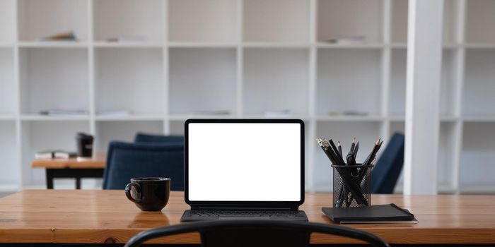 Cropped shot of workplace with tablet blank screen and office supplies in simple workspace.