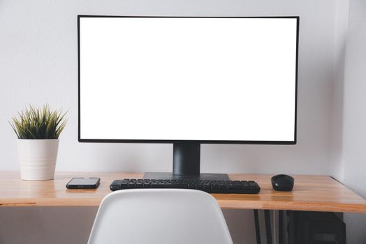 Computer monitor with white blank screen on the business desk with wireless mouse, keyboard at home office over white wall background, Photo of equipment contemporary workspace