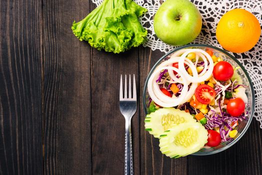 Top view of the healthy colorful fresh salad bowl with quinoa, tomatoes, and mixed greens vegetable in a dish on black wooden background, Health snack food