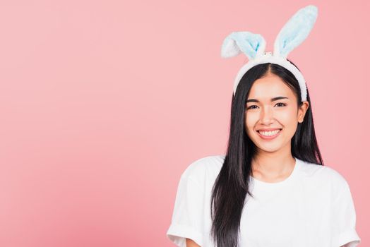 Happy Easter Day. Beautiful young woman smiling wearing rabbit ears, Portrait female happy face standing looking at camera, studio shot isolated on pink background