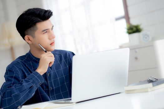Young asian business man planning working and using laptop computer on desk at home, notes about finance, male study and learning, businessman thinking idea, business and communication concept.