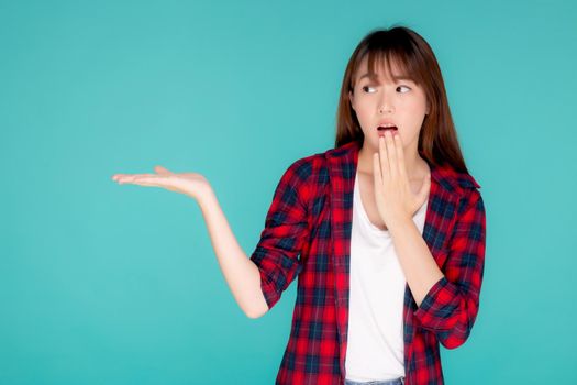Beautiful portrait young asian woman smiling gesture presenting something and excited summer holiday isolated blue background, asia girl surprise and shocked with journey, travel concept.